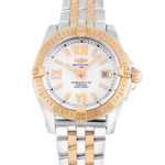 Two-tone Breitling watch with gold bezel and center links, white dial, Roman numeral markers, and date window at 3 o'clock.