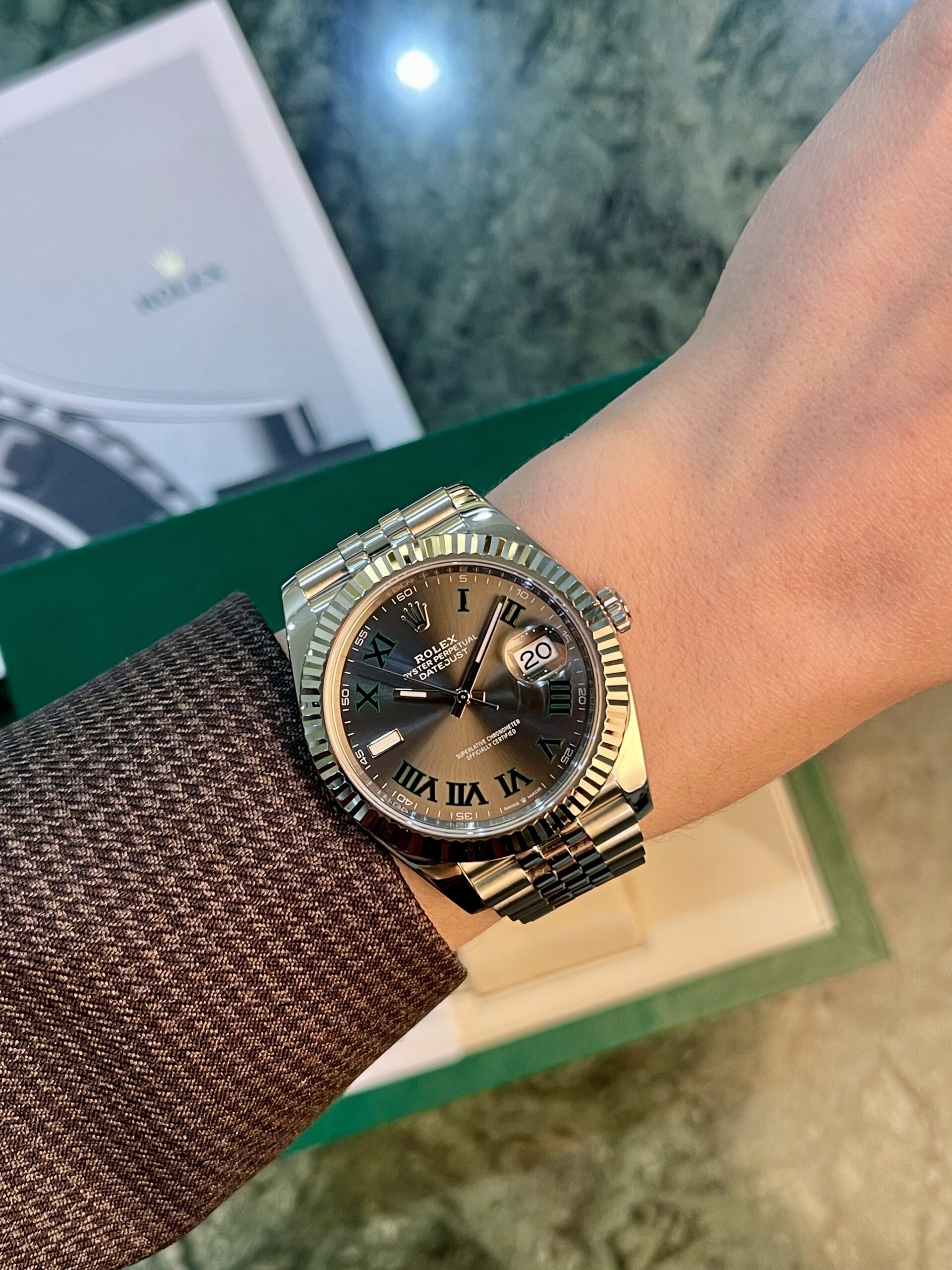 Wrist wearing a Rolex Datejust with a fluted bezel, bronze dial with Roman numerals, and date window at 3 o'clock.