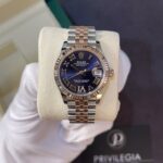 Rolex Datejust wristwatch with a blue dial, Roman numeral markers, and a two-tone silver-and-rose-gold bracelet on a display pillow.