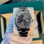 Rolex Oyster Perpetual Datejust watch with a fluted bezel and diamond hour markers on a cushion in a presentation box