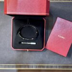 Red Cartier jewelry box opened to reveal a bracelet in black velvet tray, with a small tool resting beneath it