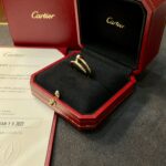 Gold Cartier ring in an open red presentation box with a black interior and gold logo.