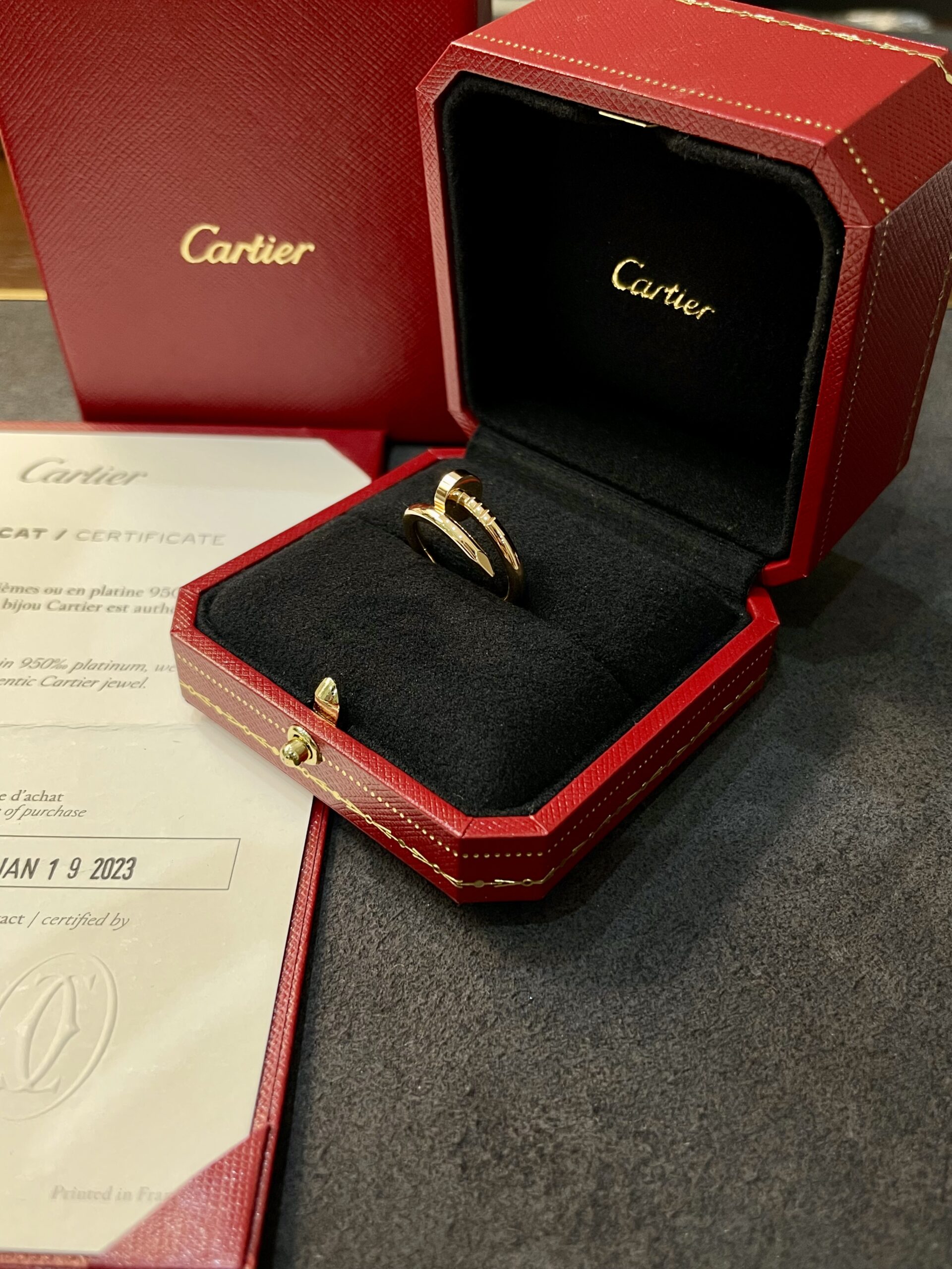 Gold Cartier ring in an open red presentation box with a black interior and gold logo.