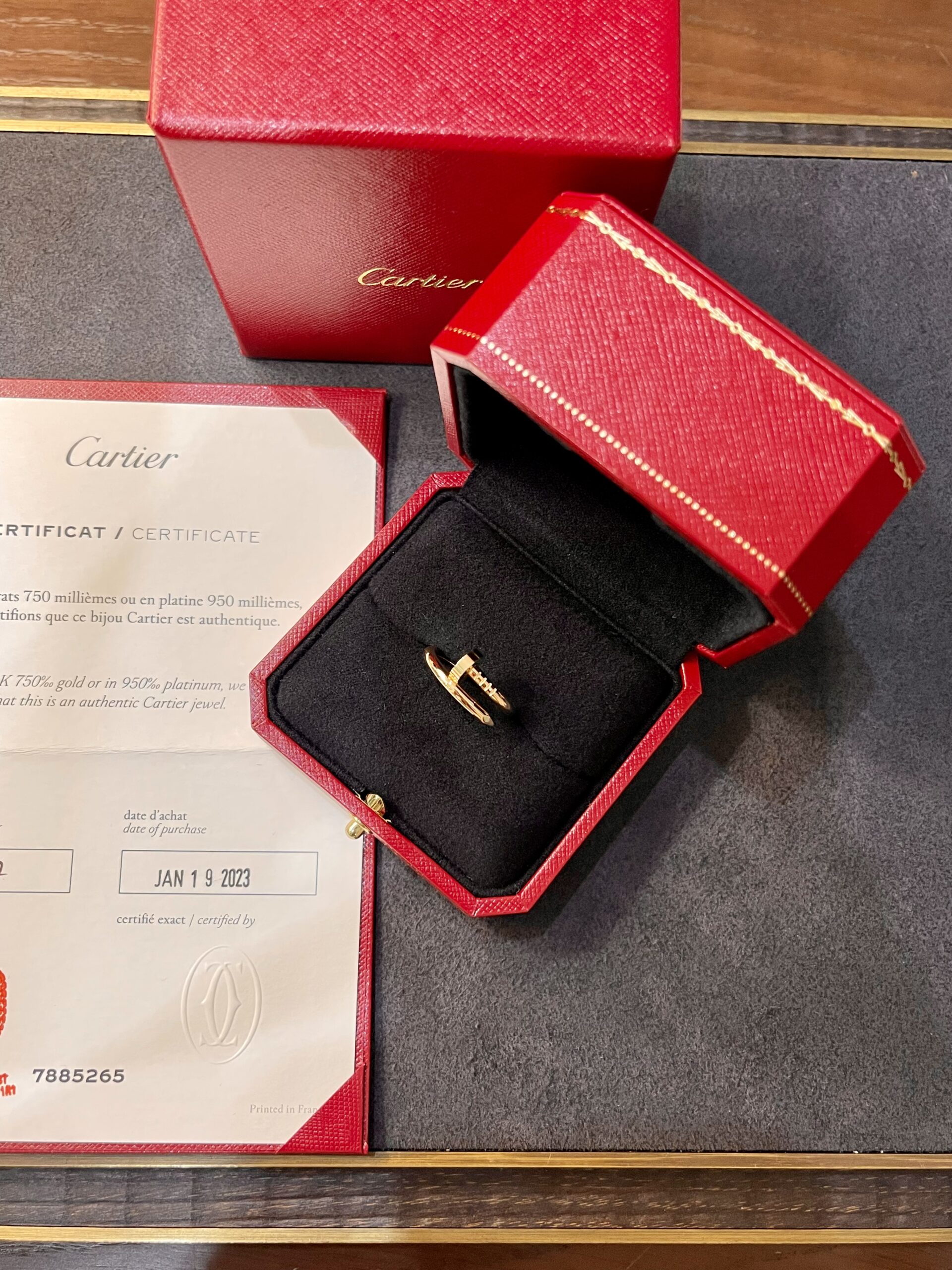 Cartier jewelry box with a gold ring displayed in a red accompanying case and certificate nearby
